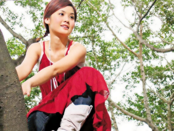 Asian woman in red dress sitting in a tree