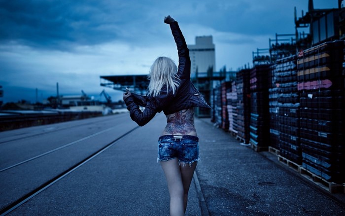 Woman with tattoos walking on a road at dusk