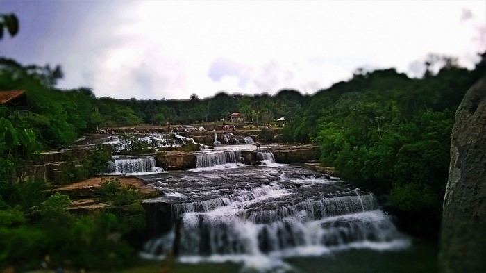 Tiered waterfall flowing over rocks surrounded by trees