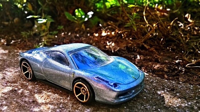 Blue Ferrari 458 Italia toy car on dirt path