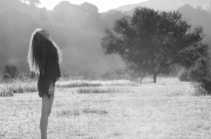 Woman with long curly hair looking up in a field