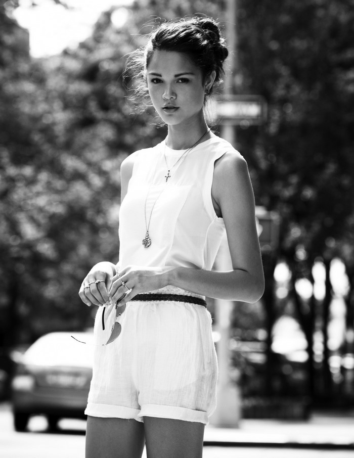 Woman in white outfit holding sunglasses