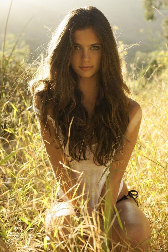 Woman with long brown hair in tall grass