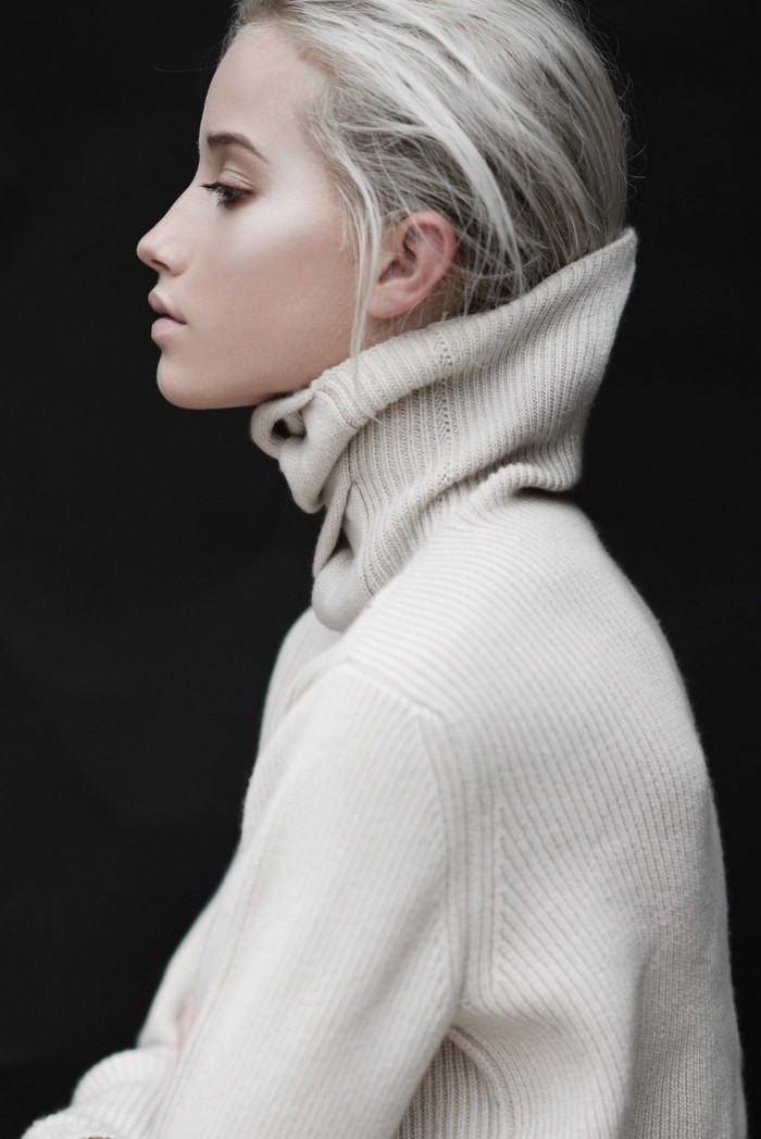 Woman with platinum blonde hair wearing a cream turtleneck