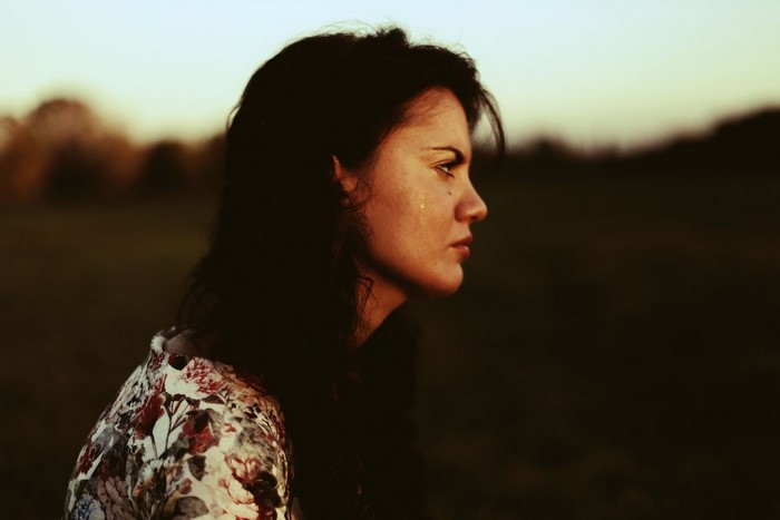 Woman crying outdoors at sunset