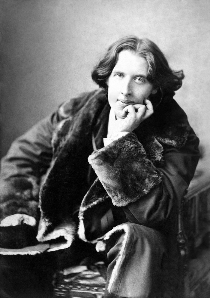 Oscar Wilde sitting and posing in a fur coat