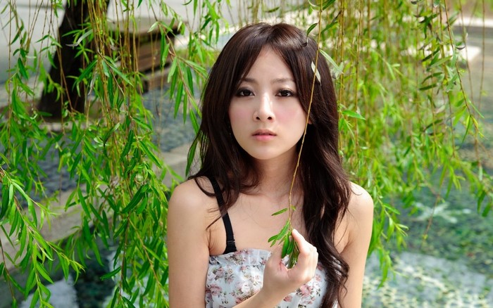 Young woman in floral dress under willow tree