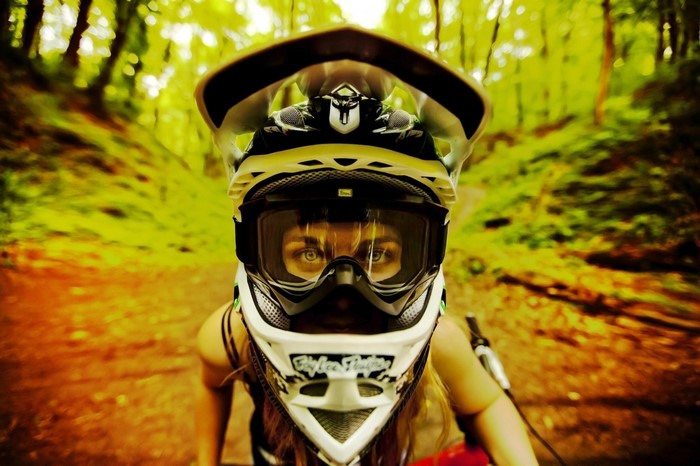 Person wearing a full-face helmet and goggles on a mountain bike