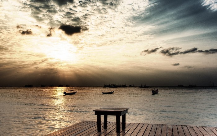 Sunset over the ocean with boats and a pier