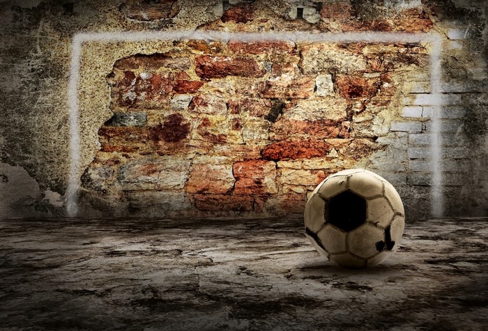 Old soccer ball against a brick wall