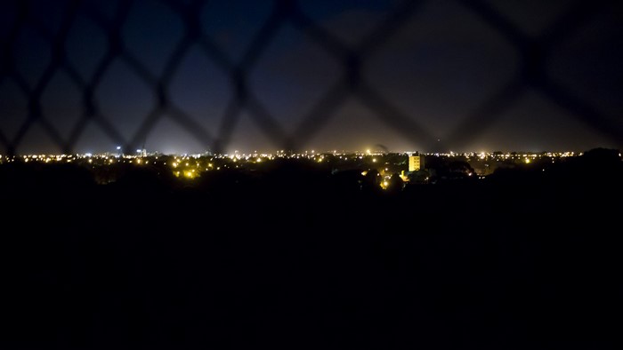 Cityscape at night seen through a fence