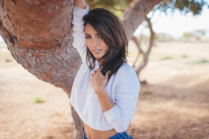 Woman leaning against a tree outdoors