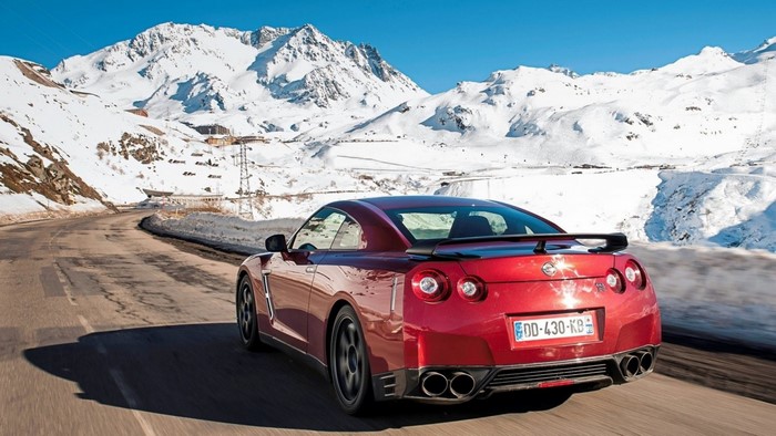 Red Nissan GT-R driving on a snowy mountain road