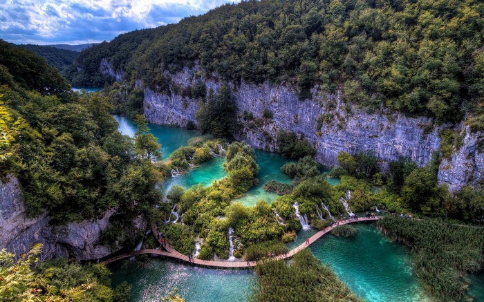Wooden walkway over turquoise lakes and waterfalls in a forest