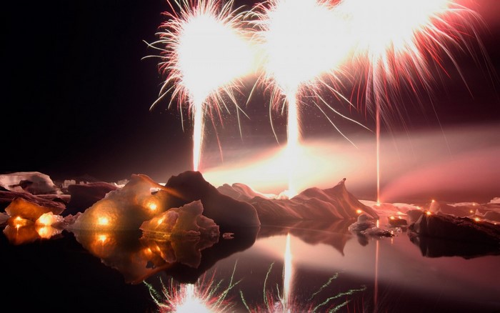 Fireworks over icebergs reflected in water at night