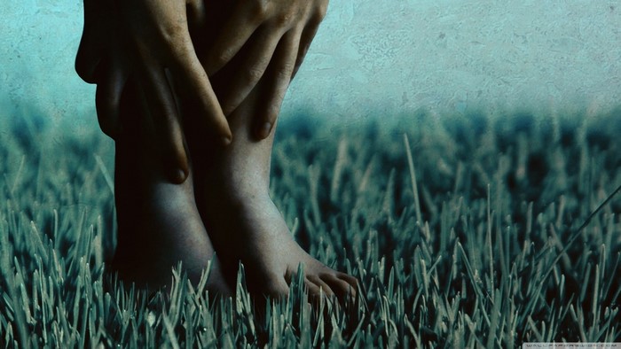 Close up of bare feet and hands in grass