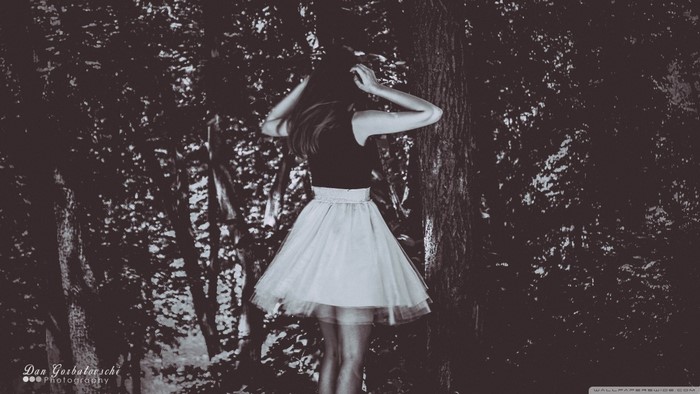 Woman in black top and white skirt in forest