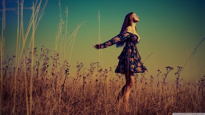 Woman in floral dress in a field at sunset