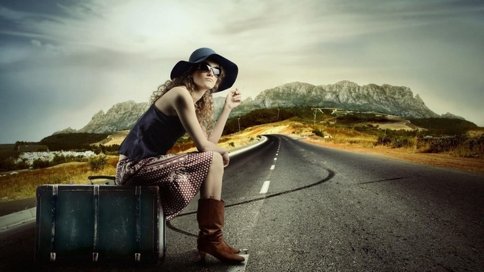 Woman with suitcase on a road