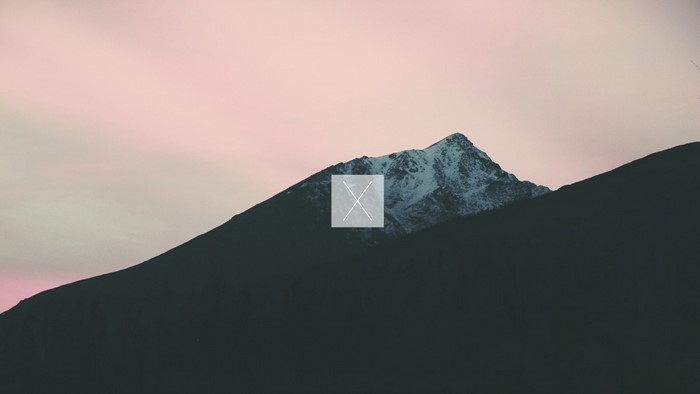 Snow-capped mountain peak at dawn with pink sky