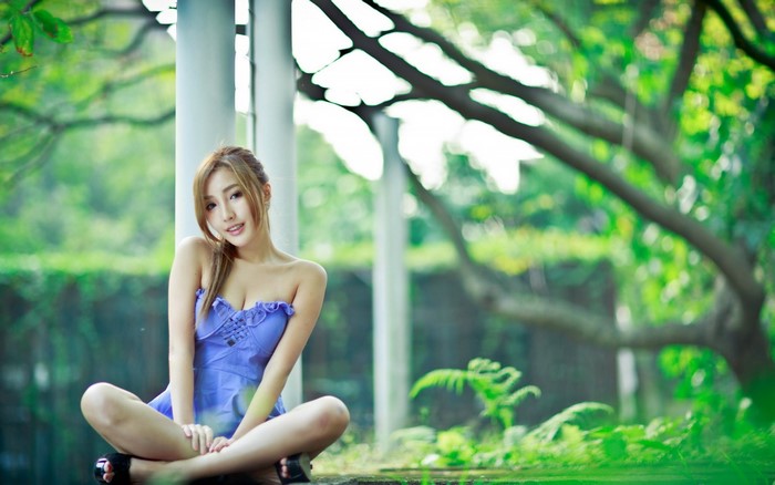 Asian woman in purple dress sitting in a garden
