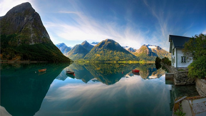 Lake reflection of mountains and a house in Norway
