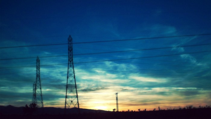 Electricity pylons against a sunset sky
