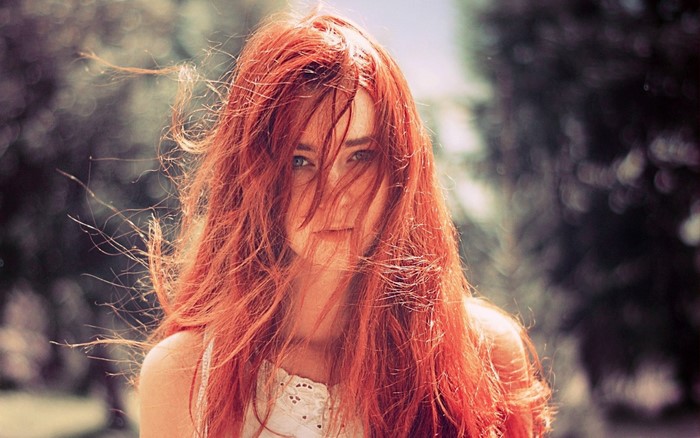 Redhead woman with hair in face outdoors
