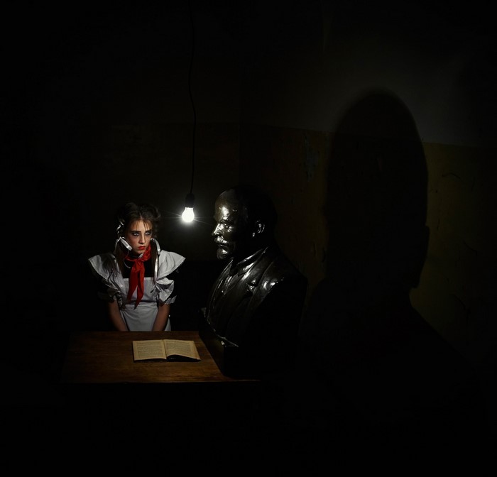 Girl in uniform and Lenin bust under a light bulb