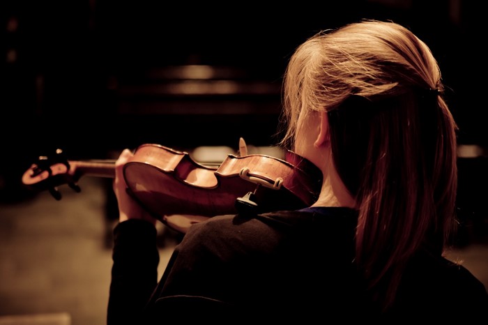 Woman playing violin in darkness