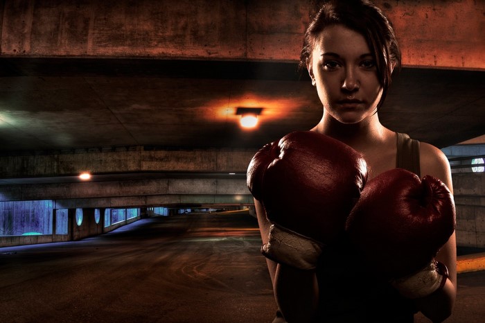 Woman boxer with red gloves in a dark parking garage