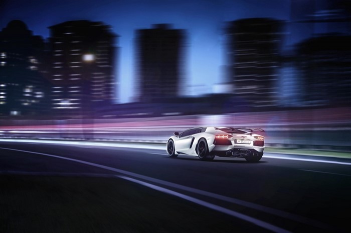White Lamborghini Aventador driving at night in a city