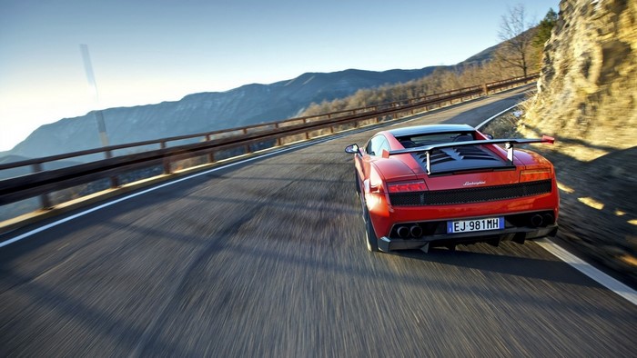 Red Lamborghini Gallardo driving on a mountain road