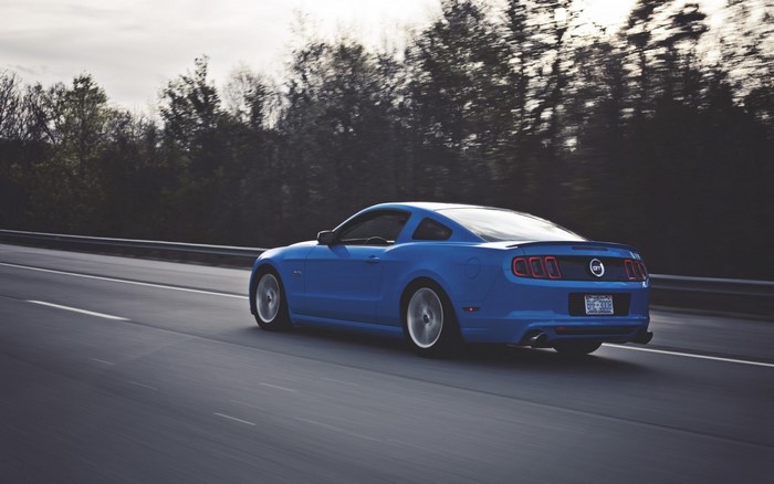 Blue Ford Mustang driving on a highway