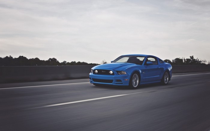 Blue Ford Mustang driving on a highway