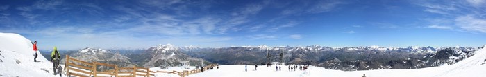 Panoramic view of snow-covered Alps with skiers and hikers