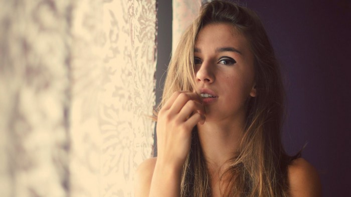 Woman with long brown hair touching her lips