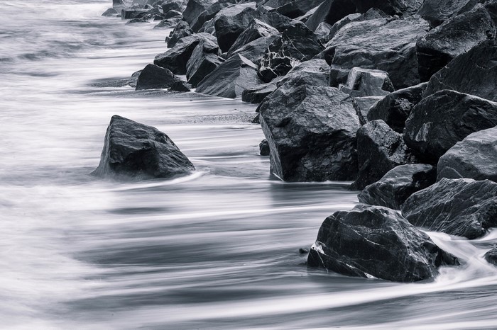 Monochrome long exposure of waves crashing on rocks