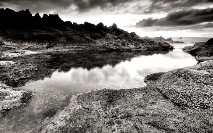 Monochrome rocky coast with tide pool reflection