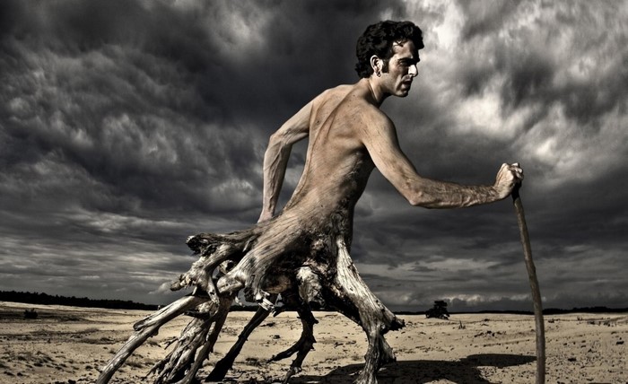 Man with tree roots for legs in a desert