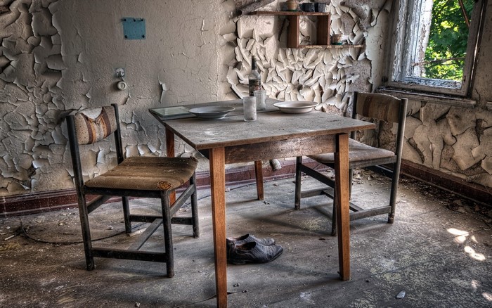 Abandoned room with table, chairs, and peeling walls