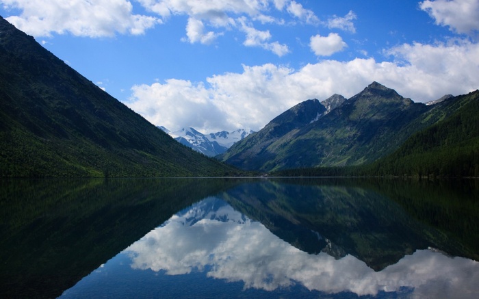 Mountain lake reflecting snow-capped peaks and clouds