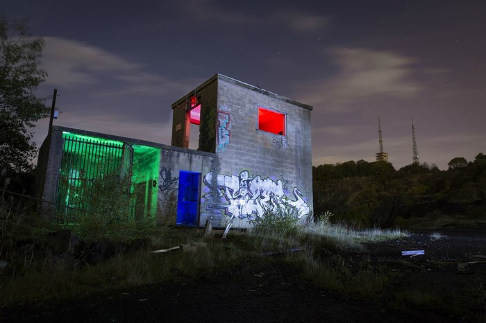 Graffiti-covered abandoned building at night with colored lights