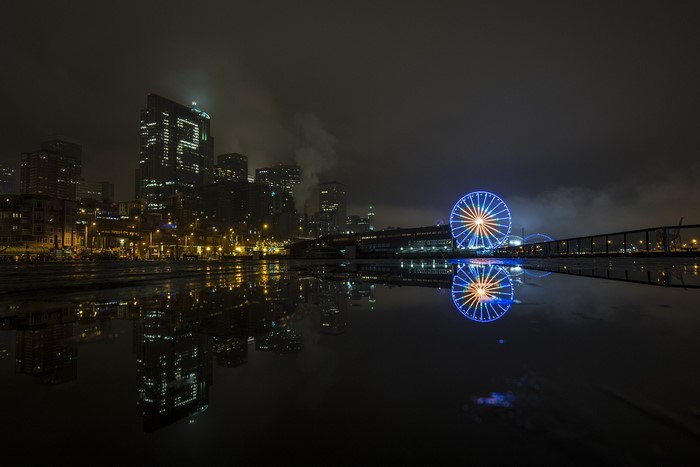 Cityscape at night with Ferris wheel and reflections