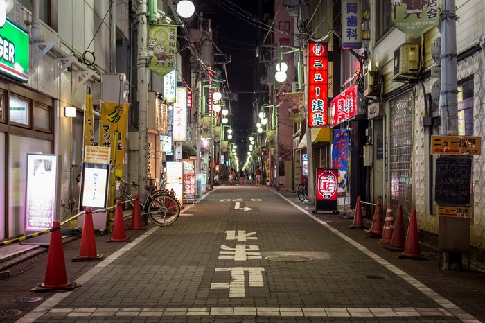 Night street in Japan with neon signs and traffic cones