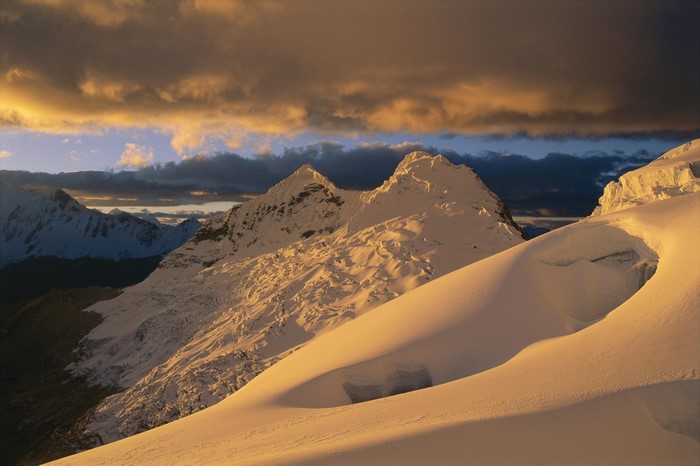 Snowy mountains at sunset with dramatic clouds