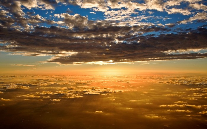 Sunset over clouds with sunbeams