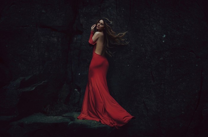 Woman in a red dress posing against rocks