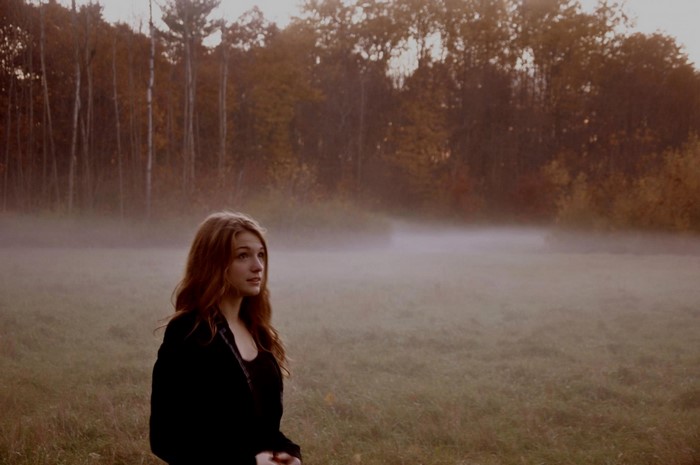 Woman in a foggy autumn forest at dawn