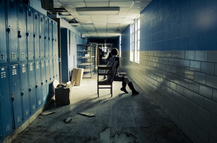 Woman sitting on a chair in an abandoned hallway